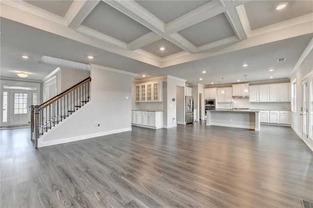 unfurnished living room featuring dark wood-type flooring, coffered ceiling, sink, crown molding, and beam ceiling