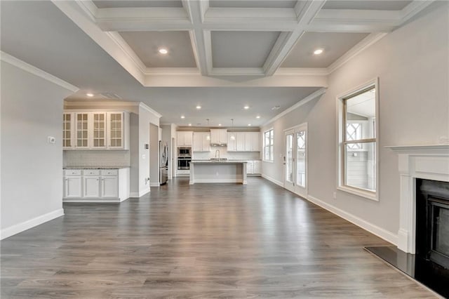 unfurnished living room with sink, crown molding, beam ceiling, coffered ceiling, and dark hardwood / wood-style flooring