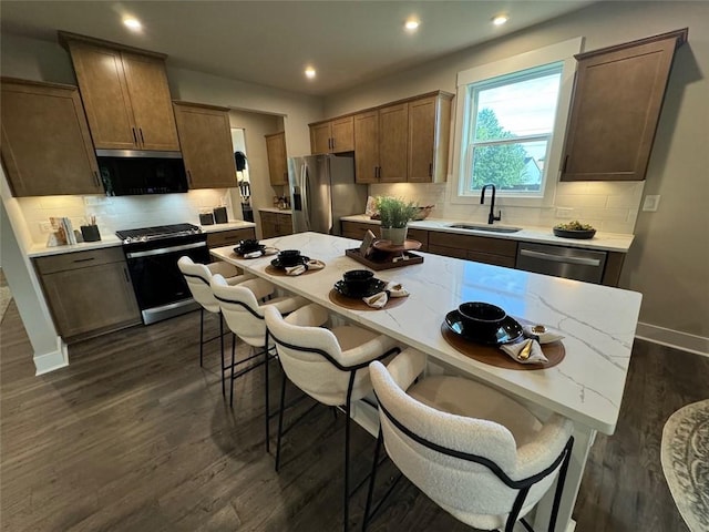 kitchen with appliances with stainless steel finishes, tasteful backsplash, sink, and dark wood-type flooring