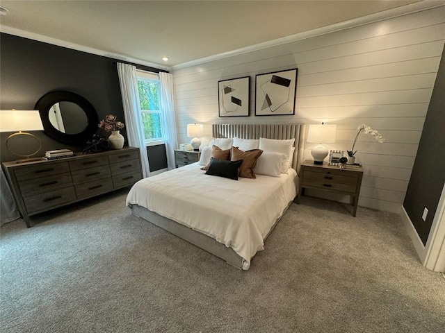 carpeted bedroom featuring wooden walls and crown molding