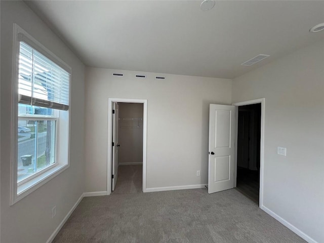 unfurnished bedroom with a closet, light colored carpet, and a spacious closet