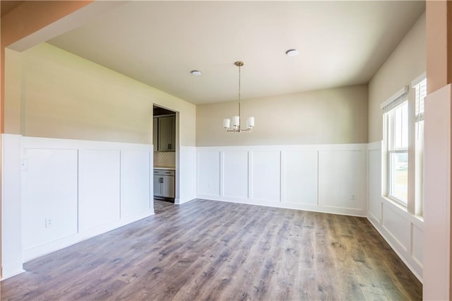 unfurnished dining area featuring a chandelier and hardwood / wood-style flooring