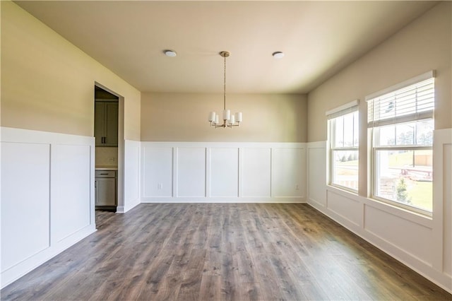 unfurnished dining area featuring hardwood / wood-style flooring and a chandelier