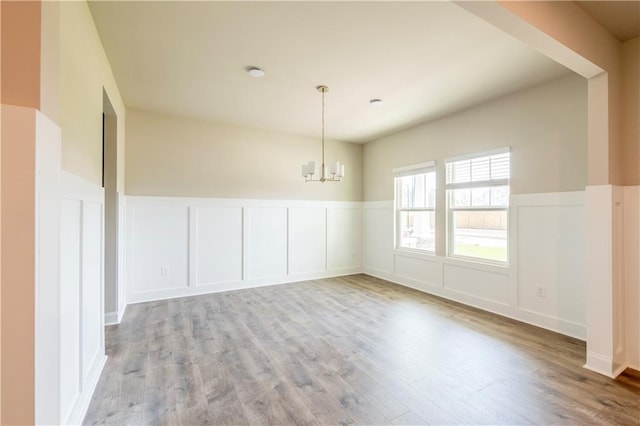 spare room with an inviting chandelier and light wood-type flooring