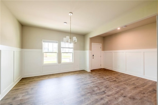 unfurnished dining area with hardwood / wood-style floors and a chandelier