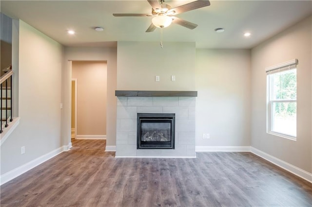 unfurnished living room with hardwood / wood-style floors, ceiling fan, and a tile fireplace