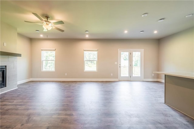 unfurnished living room with ceiling fan, a fireplace, and wood-type flooring