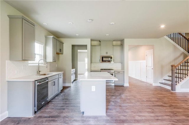 kitchen featuring gray cabinetry, a center island, hardwood / wood-style floors, appliances with stainless steel finishes, and sink