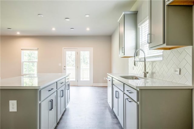 kitchen featuring tasteful backsplash, light hardwood / wood-style flooring, dishwasher, a kitchen island, and sink