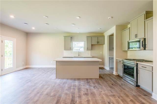 kitchen featuring a kitchen island, stainless steel appliances, sink, and light hardwood / wood-style flooring