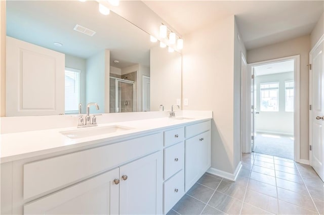 bathroom with a shower with door, vanity, and tile patterned floors