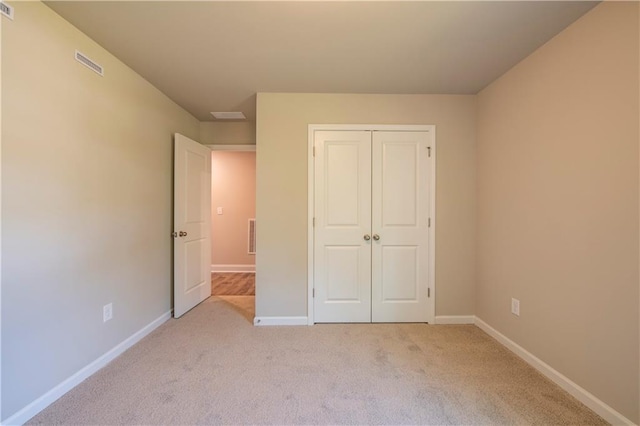 unfurnished bedroom with light colored carpet and a closet