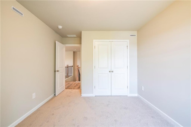 unfurnished bedroom featuring a closet and light carpet