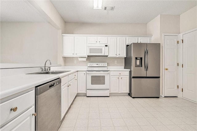 kitchen featuring visible vents, a sink, stainless steel appliances, white cabinets, and light countertops