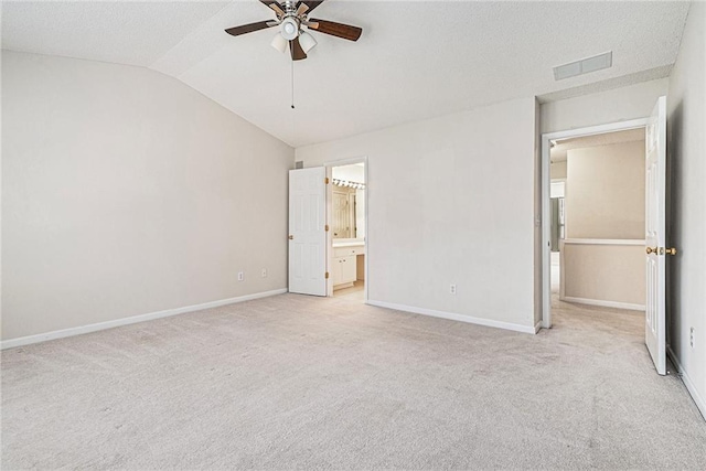 unfurnished bedroom with baseboards, visible vents, light colored carpet, ensuite bathroom, and vaulted ceiling