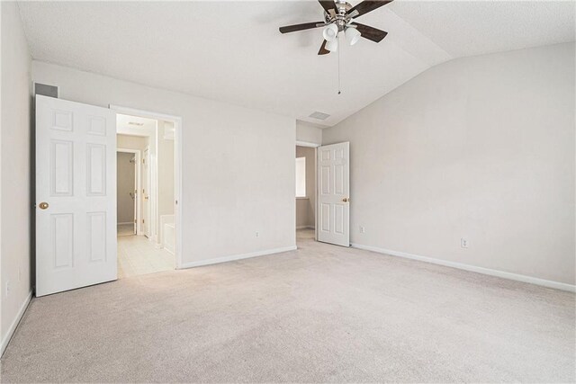 unfurnished bedroom featuring carpet, baseboards, a ceiling fan, ensuite bath, and vaulted ceiling