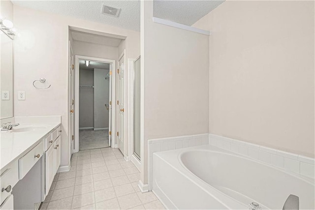 bathroom featuring a stall shower, visible vents, a textured ceiling, vanity, and a bath