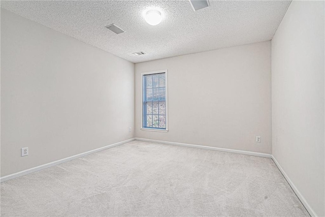 spare room featuring baseboards, a textured ceiling, visible vents, and carpet flooring