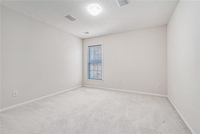 spare room featuring visible vents, carpet floors, a textured ceiling, and baseboards
