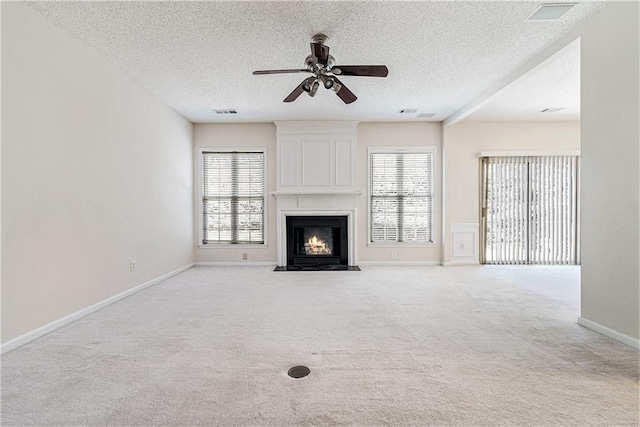 unfurnished living room featuring light carpet, a healthy amount of sunlight, a fireplace, and a ceiling fan