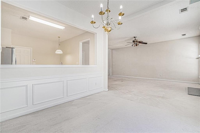 spare room with carpet floors, visible vents, a decorative wall, and ceiling fan with notable chandelier