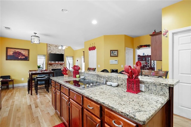 1227 Castle Point Ct SW, Conyers, GA 30094 - kitchen featuring stovetop, open floor plan, light wood-style floors, lofted ceiling, and light stone counters