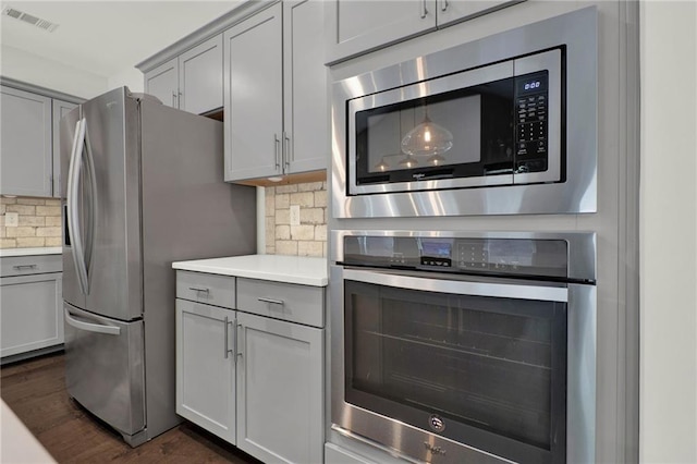 kitchen featuring stainless steel appliances, light countertops, visible vents, gray cabinetry, and tasteful backsplash