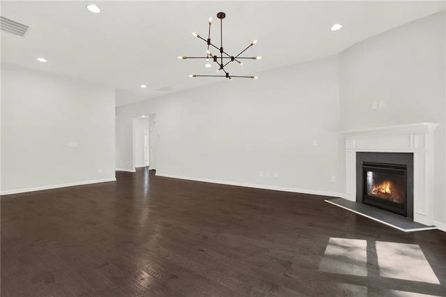 unfurnished living room featuring dark wood-style floors, a glass covered fireplace, recessed lighting, visible vents, and an inviting chandelier