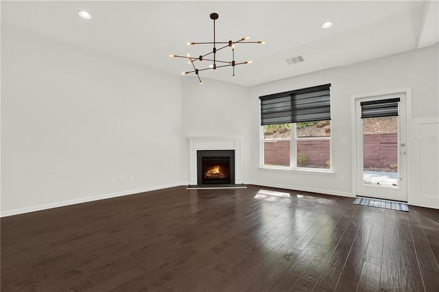 unfurnished living room featuring dark wood finished floors, visible vents, recessed lighting, a notable chandelier, and a lit fireplace