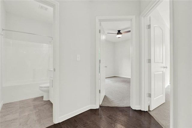 hallway featuring dark wood-type flooring, visible vents, and baseboards