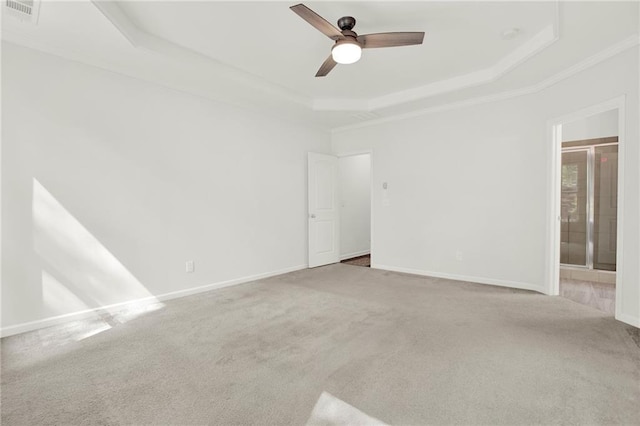 empty room featuring carpet flooring, visible vents, baseboards, ceiling fan, and a raised ceiling