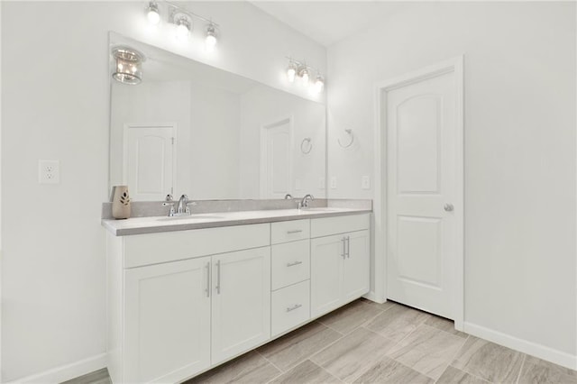 bathroom featuring double vanity, baseboards, and a sink