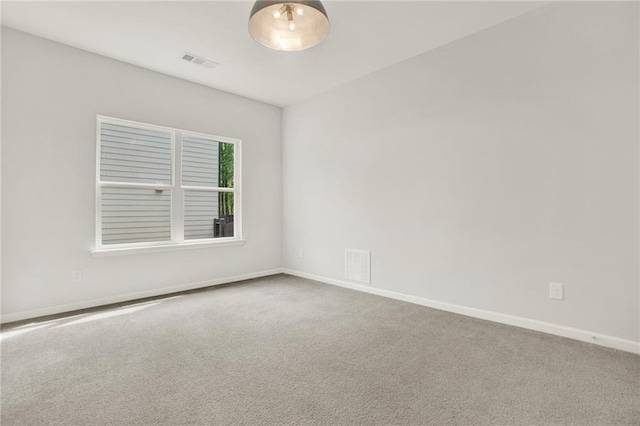 carpeted spare room featuring baseboards and visible vents