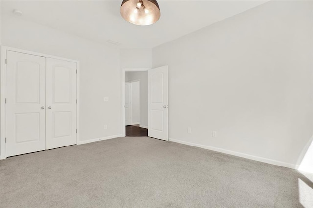 unfurnished bedroom featuring baseboards, carpet floors, and a closet