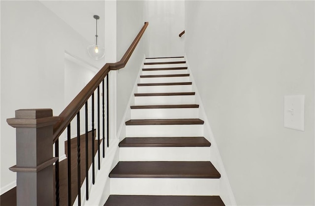 stairway featuring wood finished floors and a towering ceiling