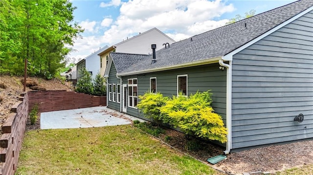 view of property exterior featuring fence, roof with shingles, a yard, and a patio