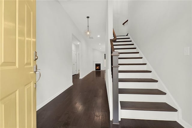 entryway featuring stairs, a warm lit fireplace, wood-type flooring, baseboards, and recessed lighting