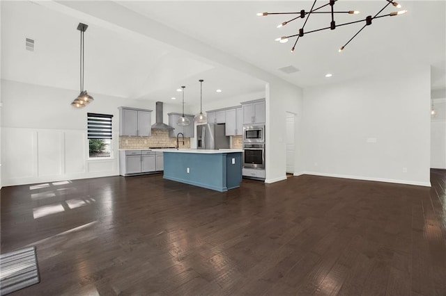 kitchen featuring stainless steel appliances, light countertops, wall chimney range hood, visible vents, and open floor plan