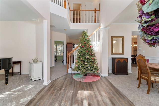 foyer featuring carpet flooring, an inviting chandelier, a high ceiling, and ornamental molding