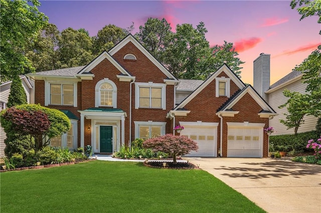 colonial house featuring a garage, a front lawn, concrete driveway, and brick siding