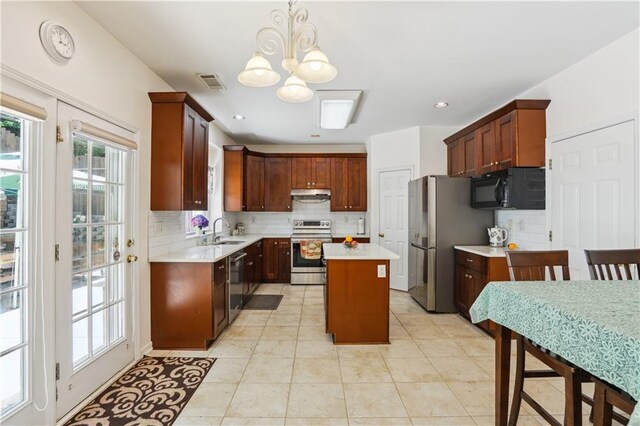 kitchen featuring a center island, light countertops, appliances with stainless steel finishes, a sink, and under cabinet range hood