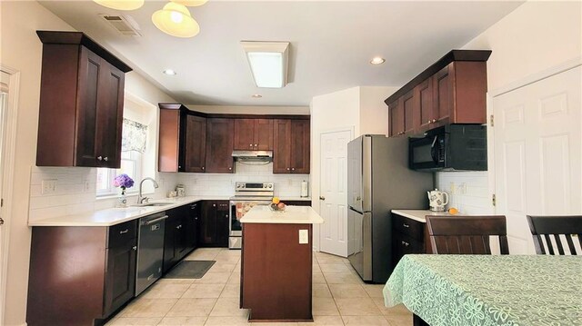 kitchen with stainless steel appliances, light countertops, a kitchen island, a sink, and under cabinet range hood