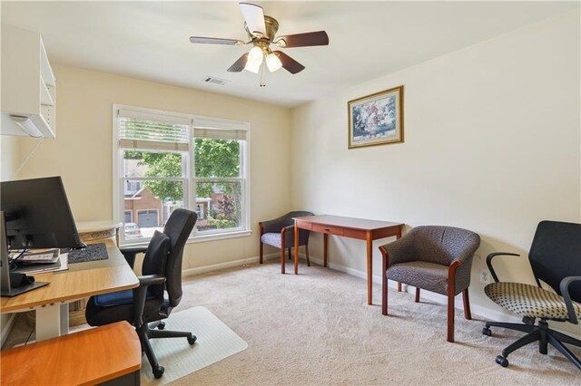 office area featuring a ceiling fan, light carpet, visible vents, and baseboards