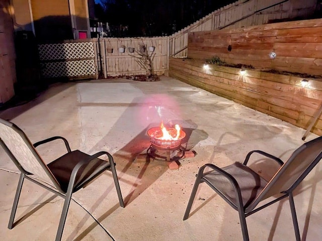 view of patio featuring fence and a fire pit