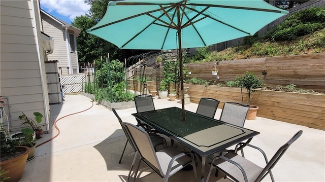 view of patio with a garden, fence, and outdoor dining space