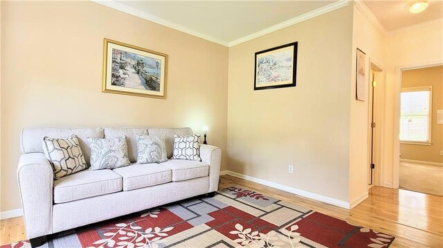 living area with baseboards, wood finished floors, and crown molding