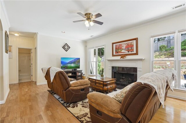 living area featuring crown molding, baseboards, a tile fireplace, and light wood-style floors