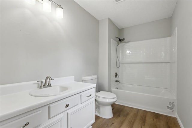 full bathroom with toilet, wood finished floors, bathtub / shower combination, a textured ceiling, and vanity