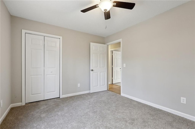 unfurnished bedroom with a ceiling fan, a closet, baseboards, and carpet flooring