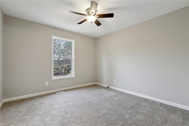 carpeted empty room featuring ceiling fan, visible vents, baseboards, and a textured ceiling